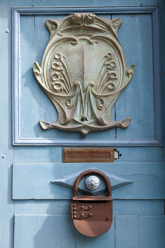 A vintage blue door in Dinan, France with ornate bas relief and rustic lock detail.